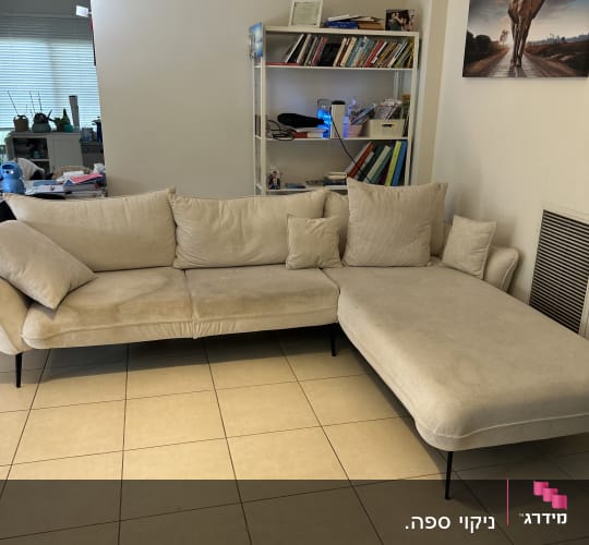 ספה בהירה בחדר מגורים עם מדף ספרים
